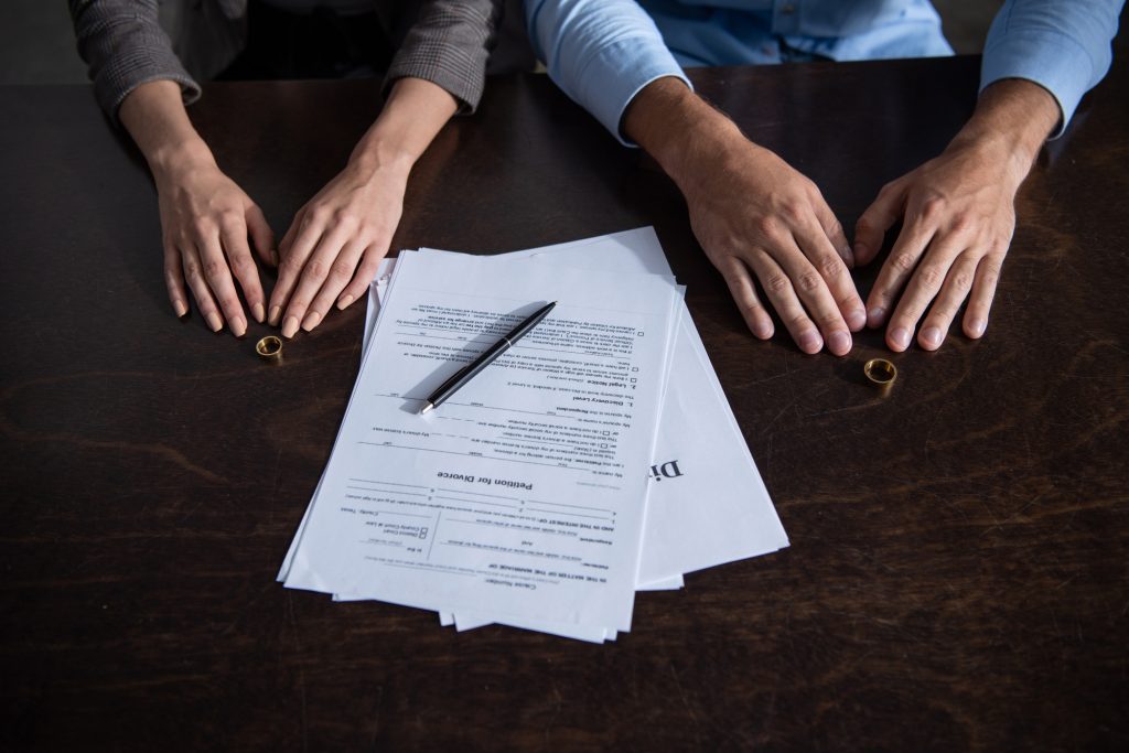 partial view of couple at table with divorce documents and rings
