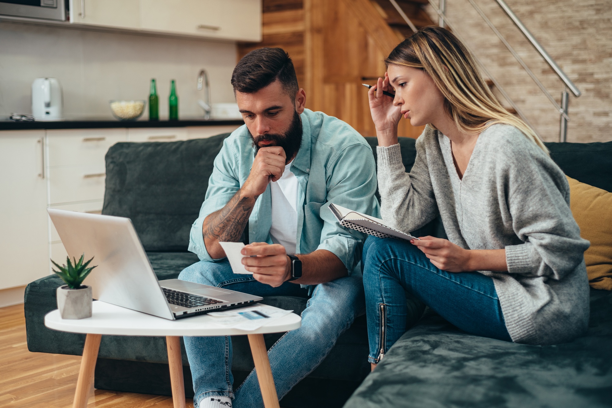 Young worried couple using a laptop for calculating their monthly budget